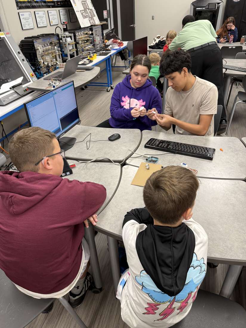 A Waller Robotics student helping younger club members wire a circuit