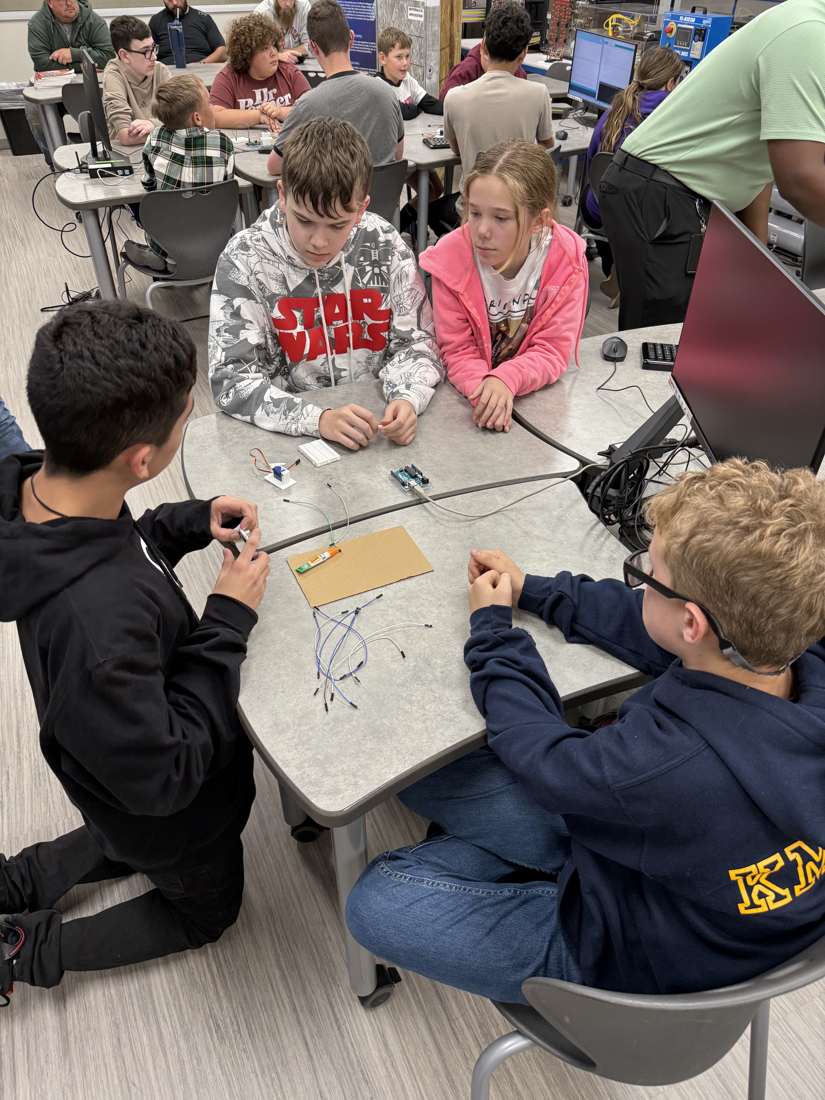 Club members building a breadboard circuit with a team mentor